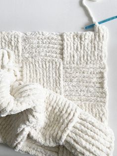 a white knitted blanket laying on top of a table next to a toothbrush