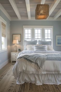 a large bed in a bedroom next to two windows and a rug on the floor