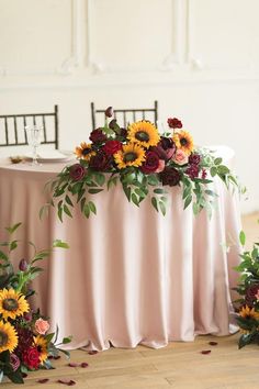 the table is set with sunflowers, roses and greenery for an elegant centerpiece