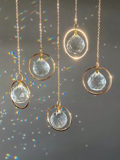 four pieces of gold and clear glass hanging from chains with sparkles in the background