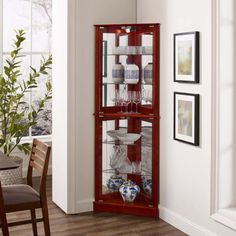 a tall wooden display case filled with wine glasses and other glassware sitting on top of a hard wood floor next to a dining room table