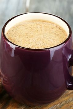 a cup of coffee sitting on top of a wooden table next to some cinnamons