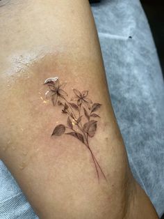 a small tattoo on the leg of a woman's lower arm with flowers growing out of it