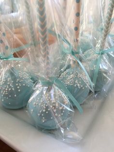 blue cake pops wrapped in cellophane and decorated with white polka dots, are sitting on a table