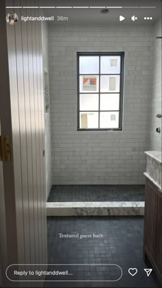 an empty bathroom with tile flooring and white brick walls, along with a large window