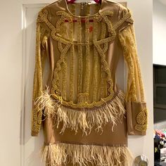 a dress hanging on a door with feathers and beads around the bottom part of it