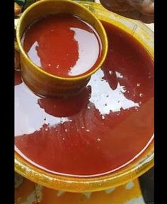 a bowl filled with red liquid sitting on top of a yellow plate next to another bowl