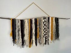 a wall hanging made out of different types of yarn and wood sticks with strings attached to it