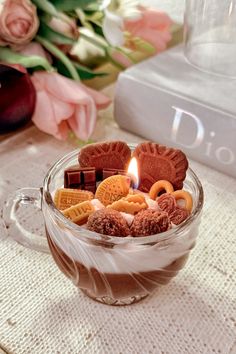 a glass cup filled with cookies and marshmallows on top of a table