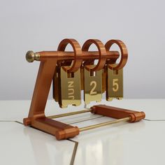 a wooden clock with three golden numbers on it's sides and two bars attached to each other