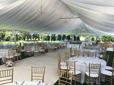 the inside of a large tent with tables and chairs set up for an outdoor function