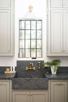 a kitchen with marble counter tops and gold faucets in front of a window