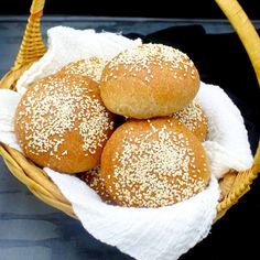 three rolls in a basket with white linen and sesame seeds on the top, sitting next to each other