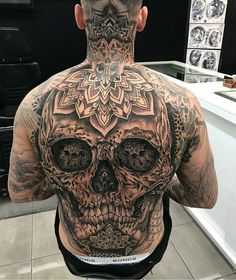 a man with a tattoo on his back is standing in front of a counter top