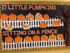 a bulletin board with little pumpkins sitting on a fence next to a small tree