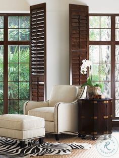 a living room with zebra rugs and large windows in the back ground, along with an ottoman