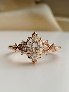 an engagement ring with three stones on top and one stone in the middle, sitting on a white surface