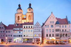 an old european town with tall buildings and a clock tower in the center at dusk