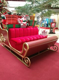 a red couch sitting in front of a christmas tree with presents on it's back