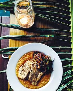 a white plate topped with meat and beans on top of a table next to a mason jar