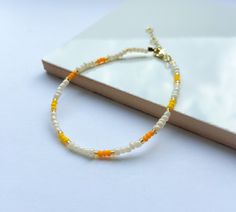 A dainty miyuki seed bead bracelet in Pearl, yellow, orange and gold.  Fastens with a gold lobster clasp and an adjustable chain to allow for various sizing. Can be stacked with other bracelets for a stylish look.   Dimensions: 20cm in total but allows for adjustable sizing. Yellow Seed Bead Bracelet, Orange Heishi Beaded Bracelets With Tiny Beads, Yellow Heishi Beaded Bracelets With Tiny Beads, Orange Tiny Beads Friendship Bracelets As Gift, Yellow Heishi Beads Bracelet With Tiny Beads, Orange Tiny Beads Friendship Bracelet As Gift, Orange Friendship Bracelets With Tiny Beads As Gift, Handmade Orange Heishi Beads Friendship Bracelets, Yellow Beaded Bracelets With Tiny Beads As A Gift