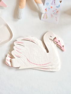 two white swan shaped napkins sitting on top of a table next to other items