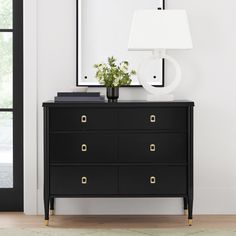 a black dresser with a white lamp next to it