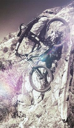 a man riding a bike up the side of a rock wall in black and white