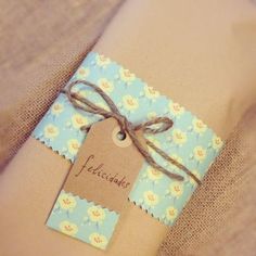 a package wrapped in brown paper with a blue flower pattern and a tag attached to it