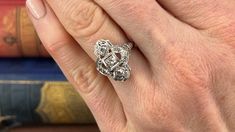 This fabulous Art Deco circa 1920s dinner ring features a pierced design with milgrain edging and etched floral designs. The ring is accented with nine (9) bead set old European cut diamonds. The ring measures 18.6mm at the top, rises 5.9mm above the finger, and tapers to 1.1mm wide by 0.7mm thick at the base of the shank. It is currently a size 5.5. Two of the diamonds have very minor chipping that cannot be seen without jewelers magnification. Art Deco Diamond Filigree Ring In Diamond White, Art Deco Sterling Silver Filigree Ring With Diamond Cut, Collectible Art Deco Filigree Ring With Diamond Cut, Silver Art Deco Intaglio Ring, Art Deco Platinum Diamond-studded Jewelry, 1920s Art, 1920s Art Deco, European Cut Diamonds, Diamond Cuts