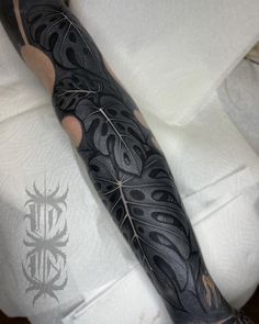 a man's arm covered in black ink with an intricate design on the arm