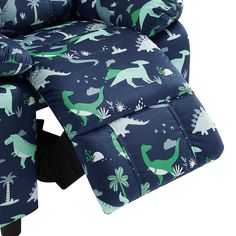 a child's reclining chair with dinosaurs on blue and green fabric, sitting in front of a white background