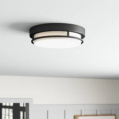 a black ceiling light hanging from the ceiling in a room with white walls and wood paneling