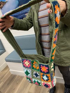 a woman holding a crocheted purse in her hands