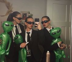 three people in suits and sunglasses are taking a selfie with alien balloons on their heads