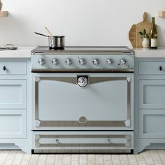 an old fashioned stove in a kitchen with blue cupboards and white counter tops on the wall