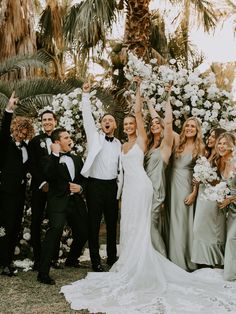 a group of people standing next to each other in front of a flower covered wall