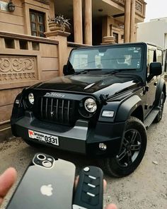 a black jeep parked in front of a building with two cell phones next to it