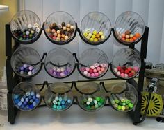 there is a rack that has many different colors of beads on it and some are in bowls