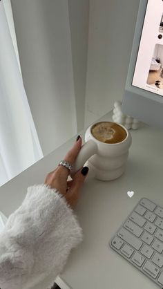 a woman's hand on a computer mouse next to a cup of coffee