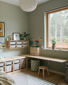 a bedroom with a desk and shelves in front of a large window