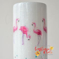 pink flamingos are painted on the side of a white cup with glitter flakes