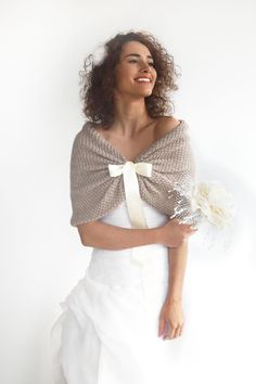 a woman with curly hair wearing a white dress and holding a flower in her hand