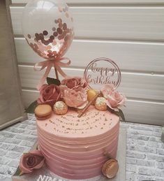 a pink birthday cake decorated with flowers and balloons