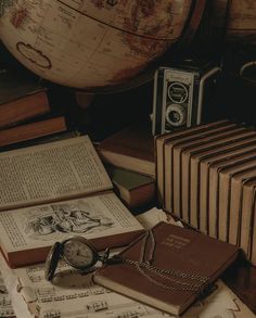 an open book sitting on top of a pile of books next to a pocket watch