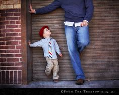 a man standing next to a little boy in front of a garage door wearing a tie