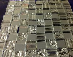 a close up view of some glass tiles on a counter top with silver and black accents