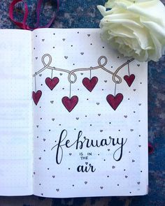 an open notebook with hearts hanging from it and the words, february in the air