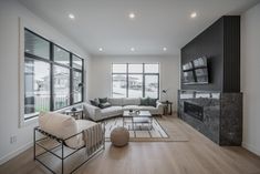 a large living room with wood floors and white couches in front of a flat screen tv mounted on the wall