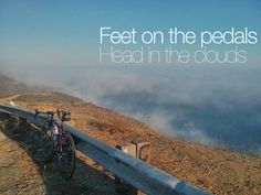 there is a bike that is parked on the side of a hill with clouds in the background